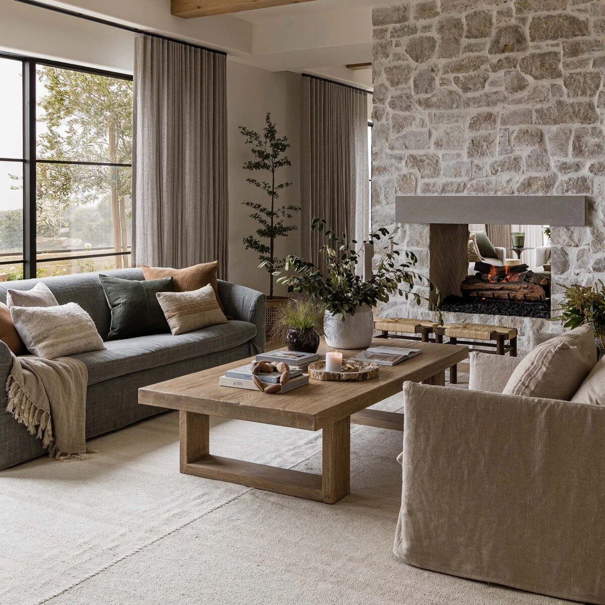 Rustic farmhouse living room featuring a grand natural stone fireplace and exposed timber ceiling rafters—traditional retreat in Siruvani.